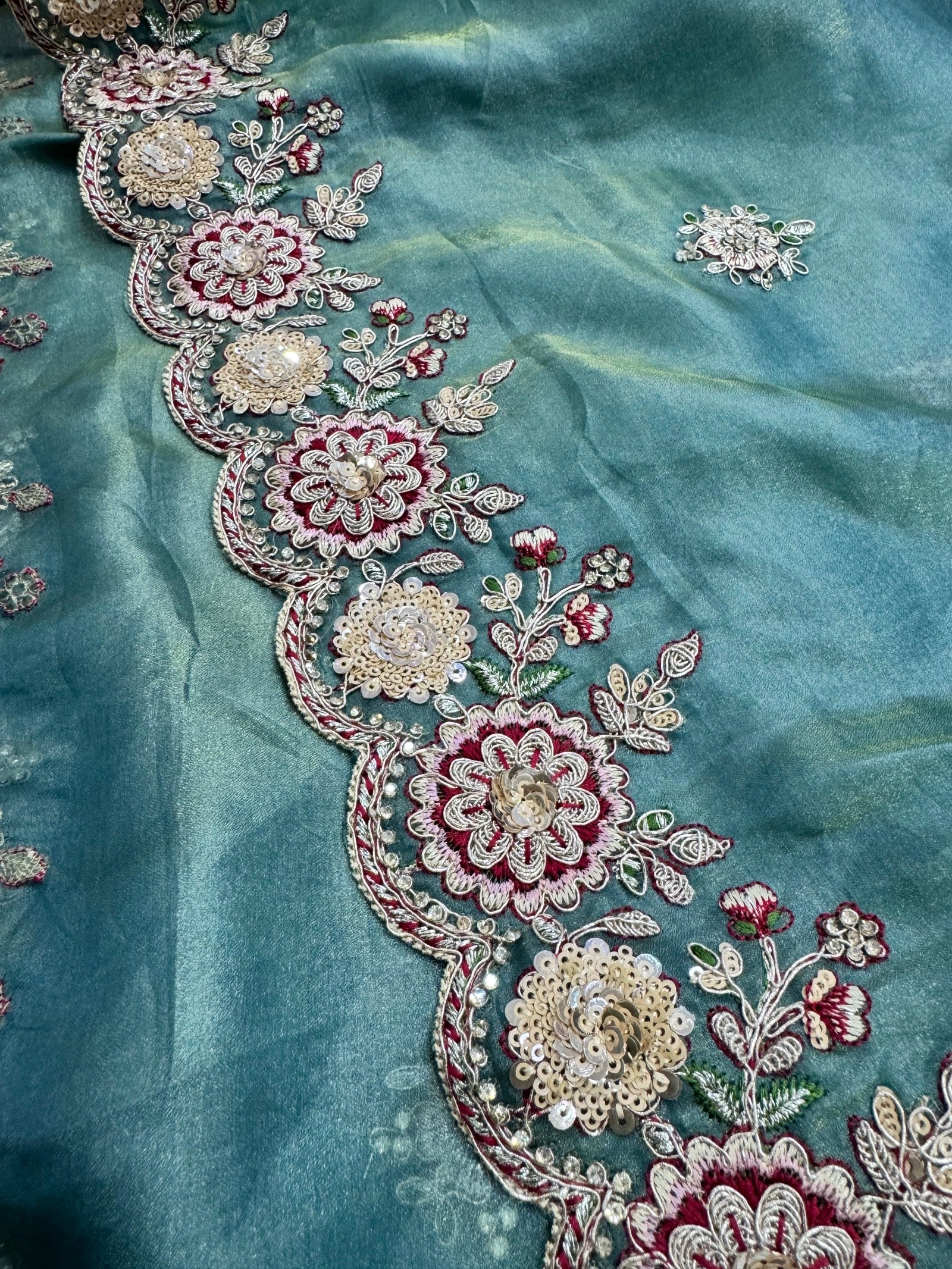 Close-up of intricate floral embroidery on a teal fabric