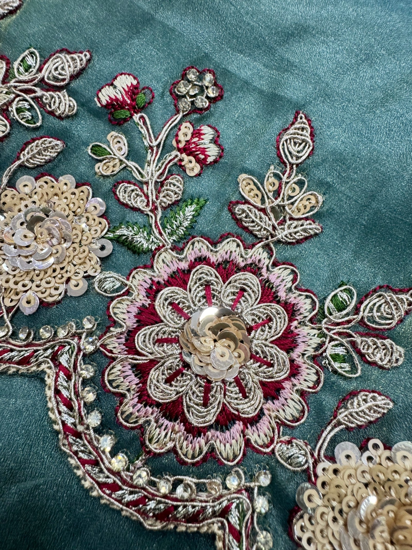 Close-up of intricate floral embroidery on a teal fabric background