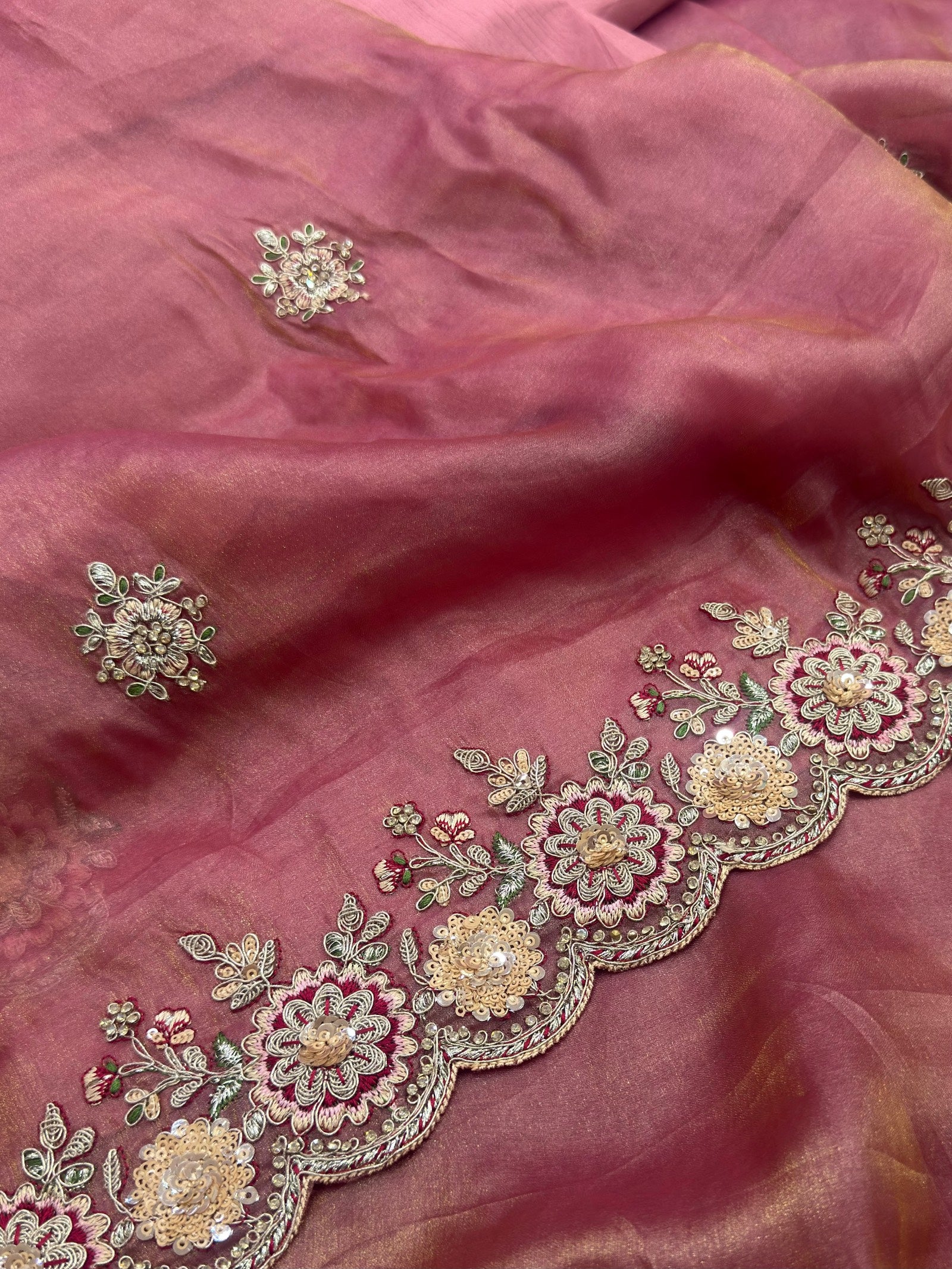 Pink fabric with intricate gold and green embroidery