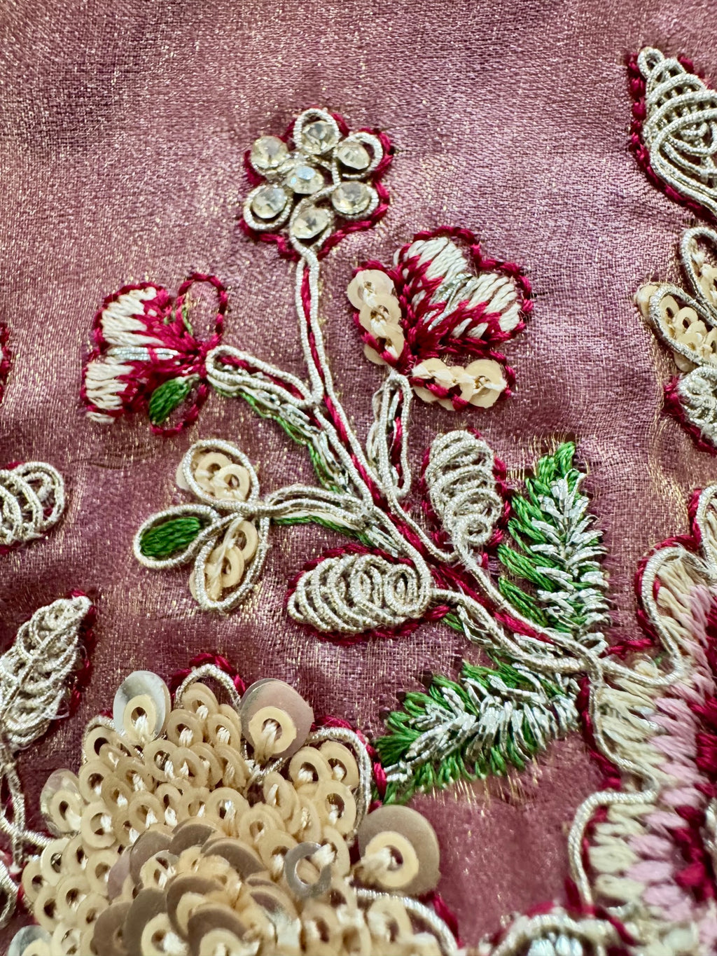 Close-up of intricate floral embroidery on a pink fabric background