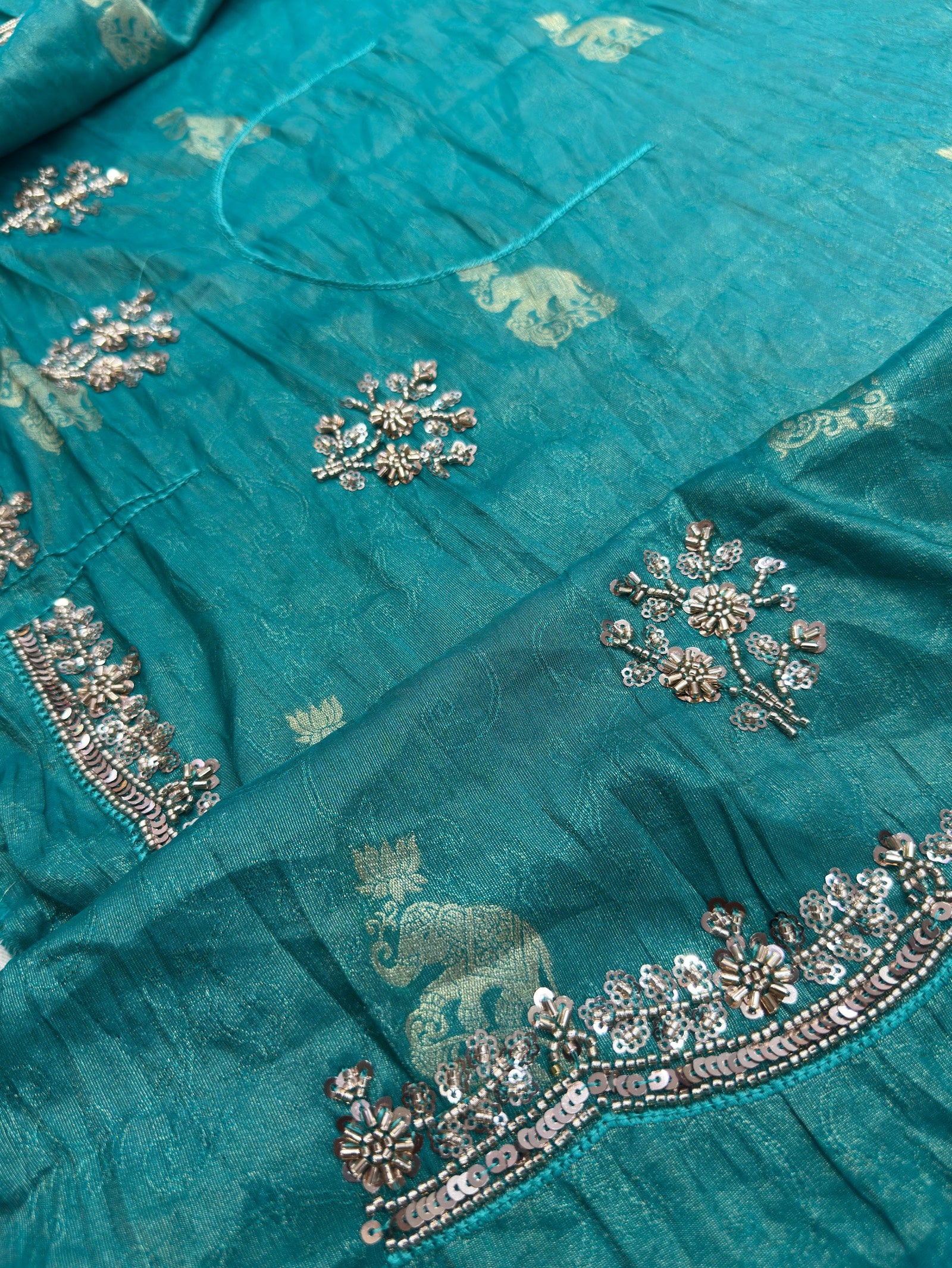 Close-up of a teal fabric with intricate silver embroidery