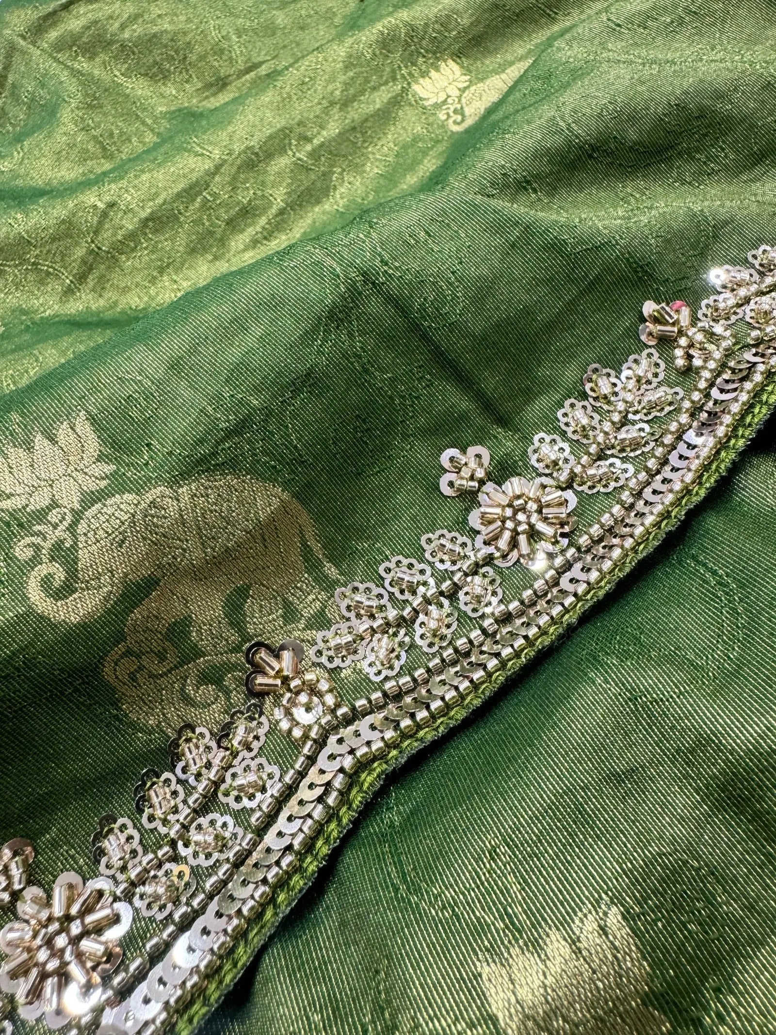 Green fabric with floral embroidery and an elephant design