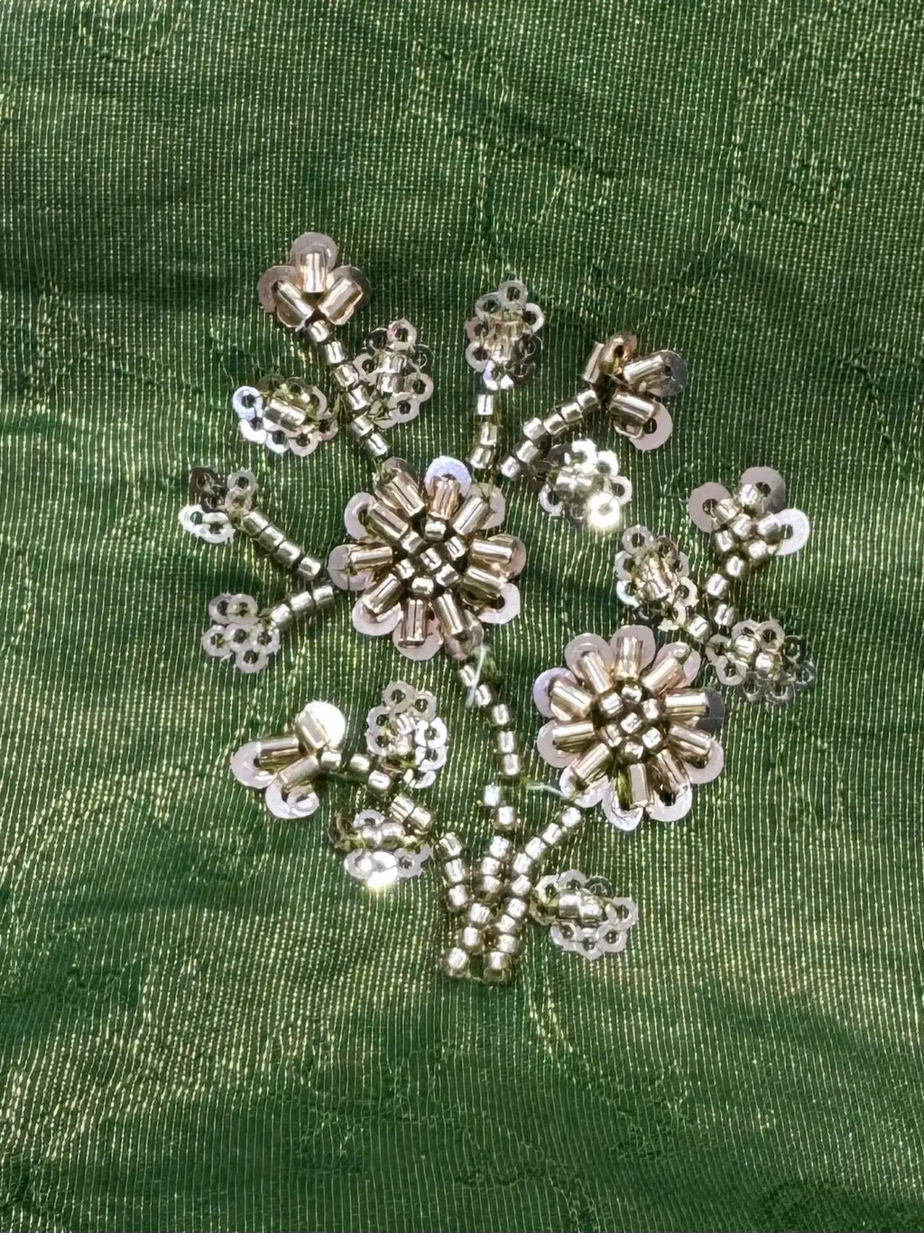 Decorative snowflake with beads on a green fabric background