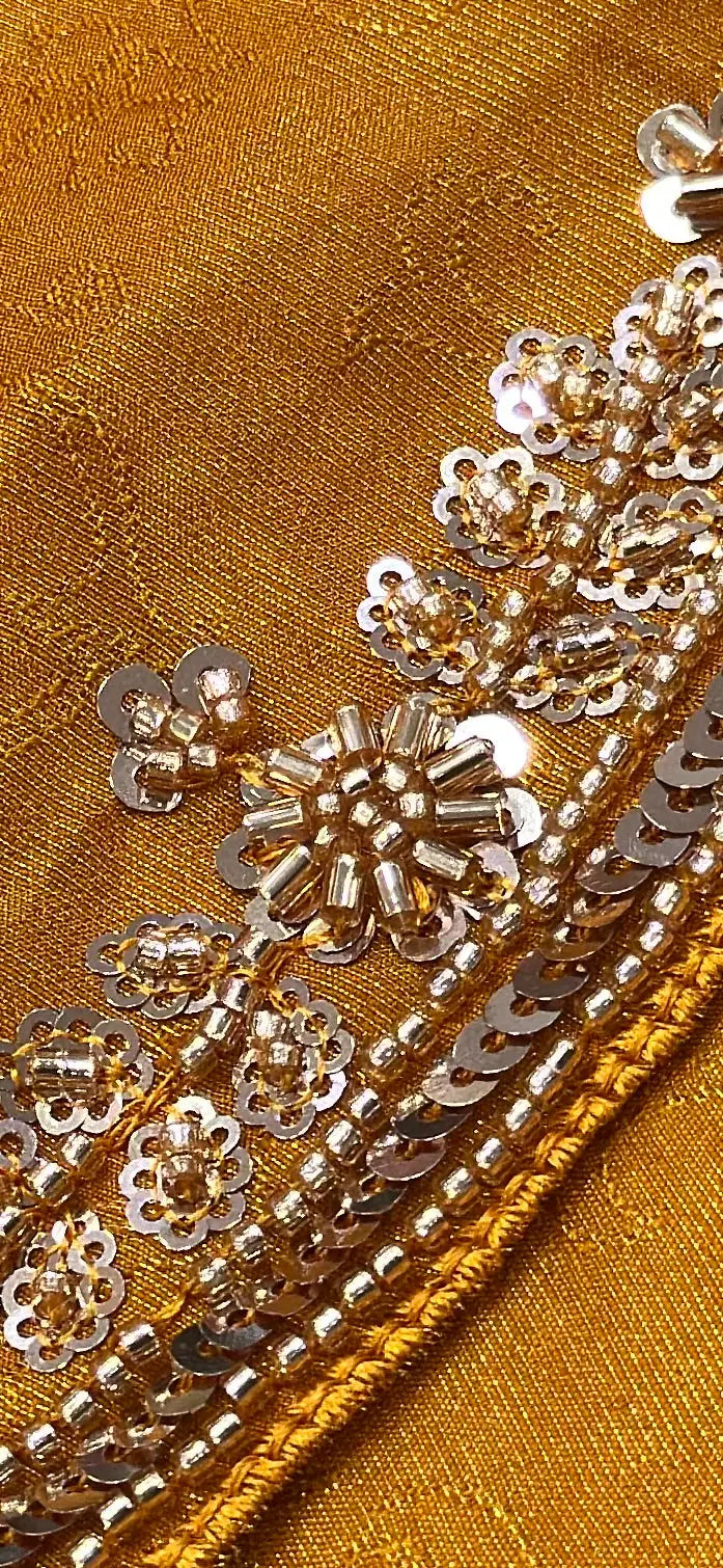 Macro shot of intricate cutdana and sequin embroidery on self woven mustard yellow silk saree