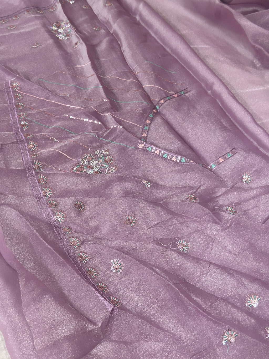 Close-up of a purple fabric with intricate embroidery and embellishments.