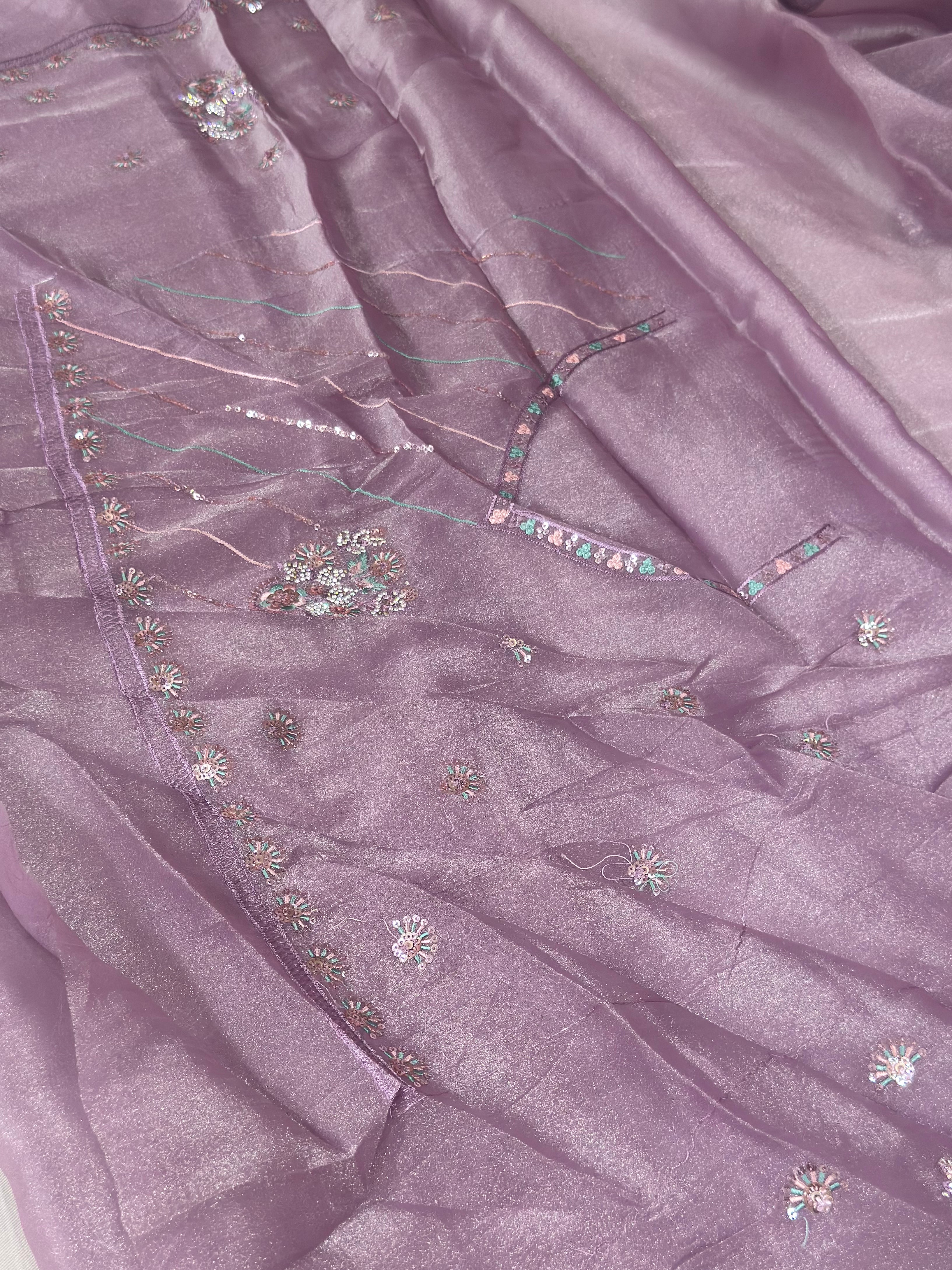 Close-up of a purple fabric with intricate embroidery and embellishments.
