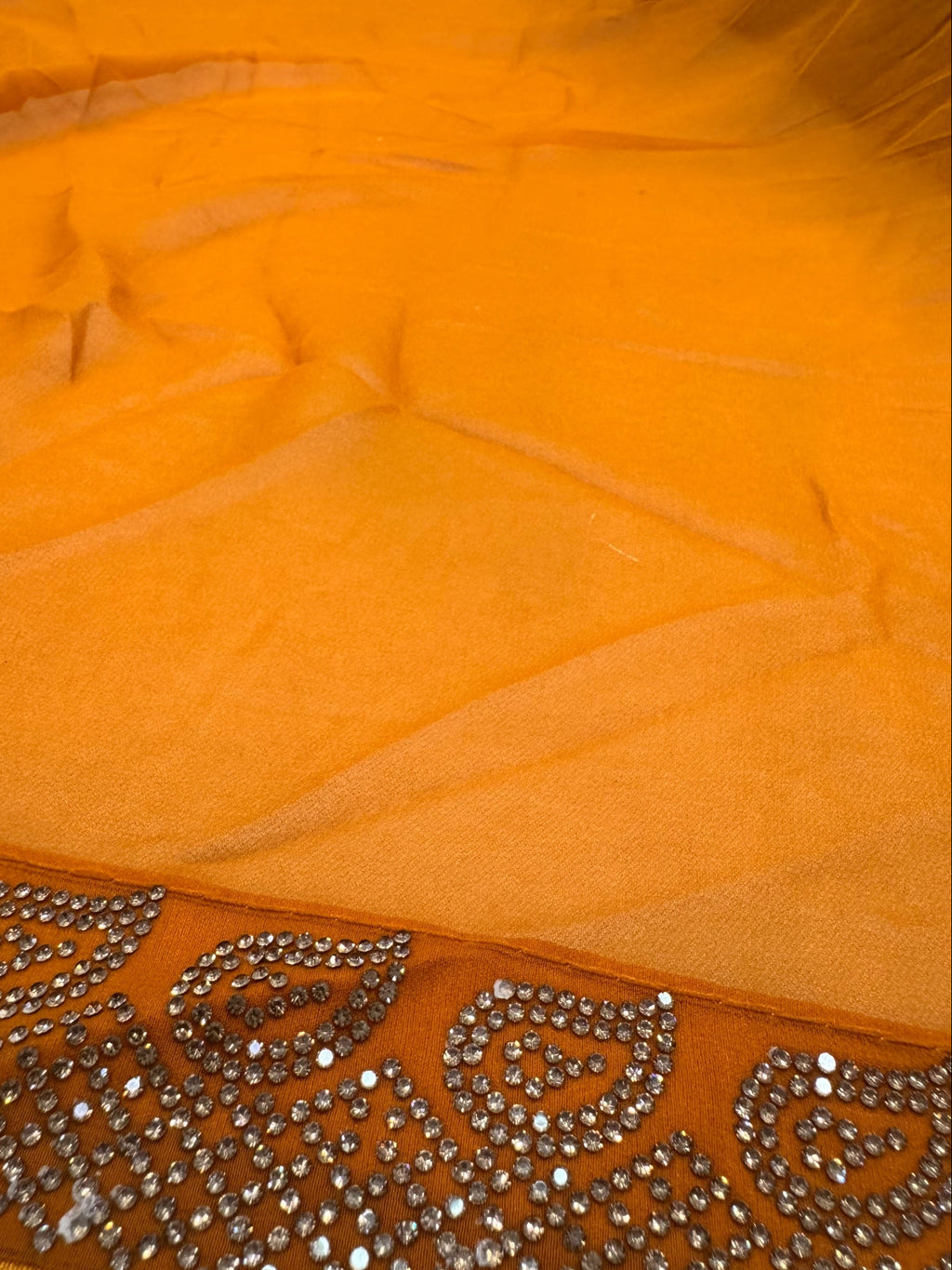 Close-up of orange fabric with intricate silver embroidery