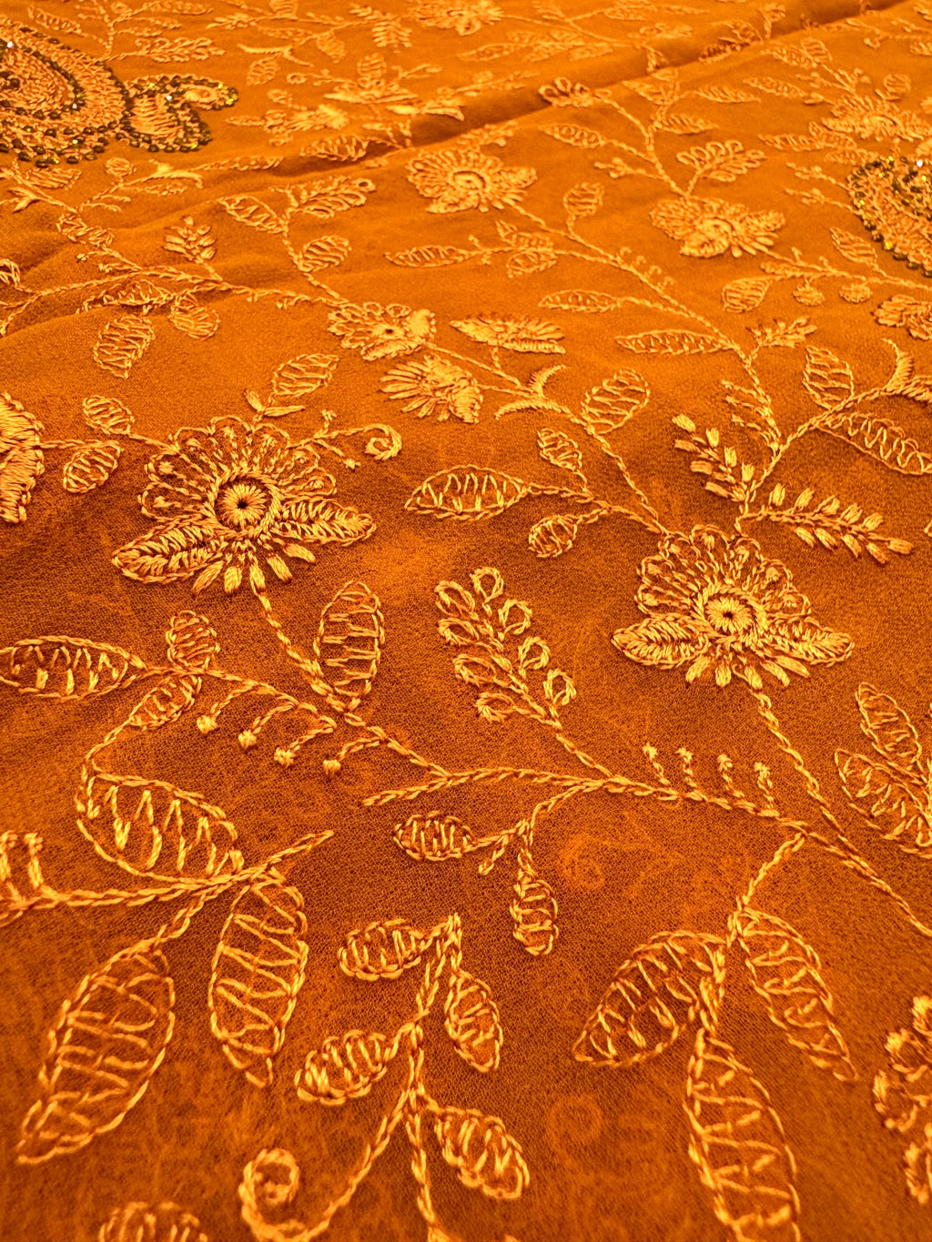 Close-up of orange fabric with floral embroidery