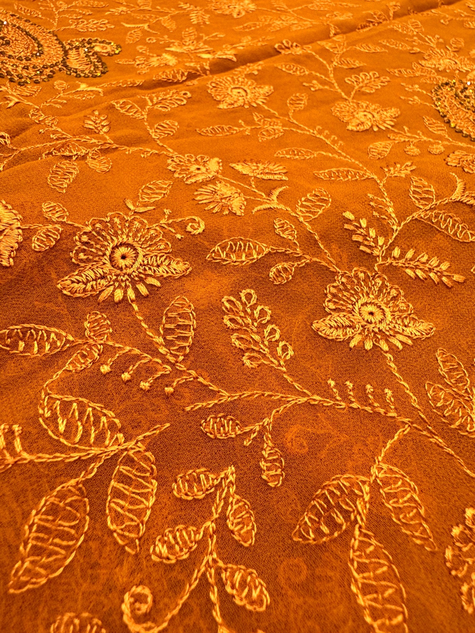 Close-up of orange fabric with floral embroidery