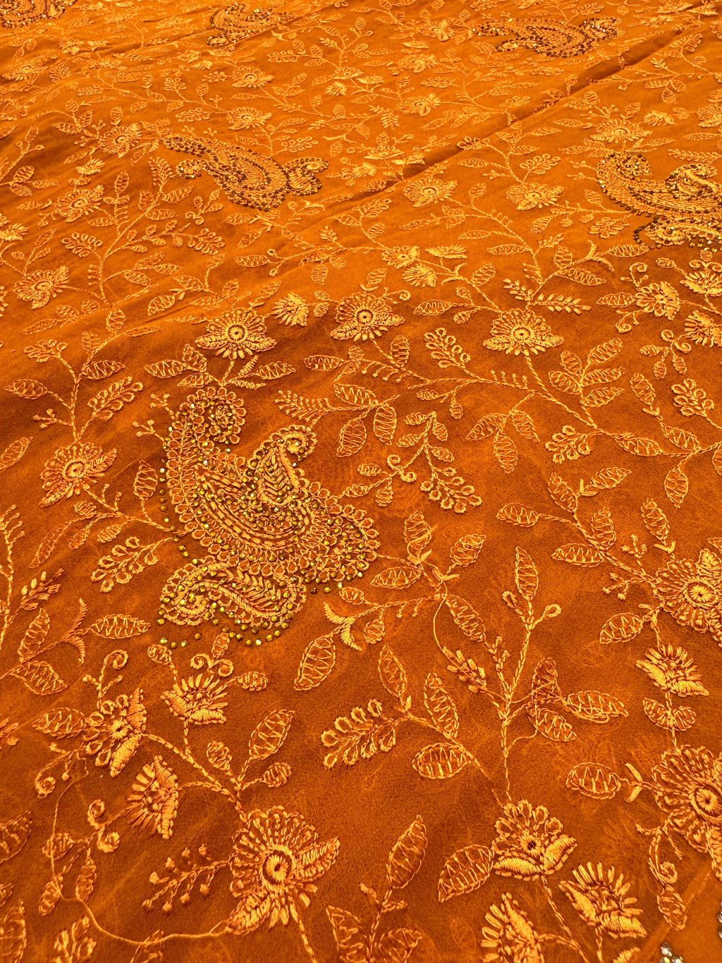 Orange fabric with intricate gold floral and paisley patterns