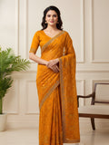 Woman wearing a orange saree with a silver embroidered border indoors.