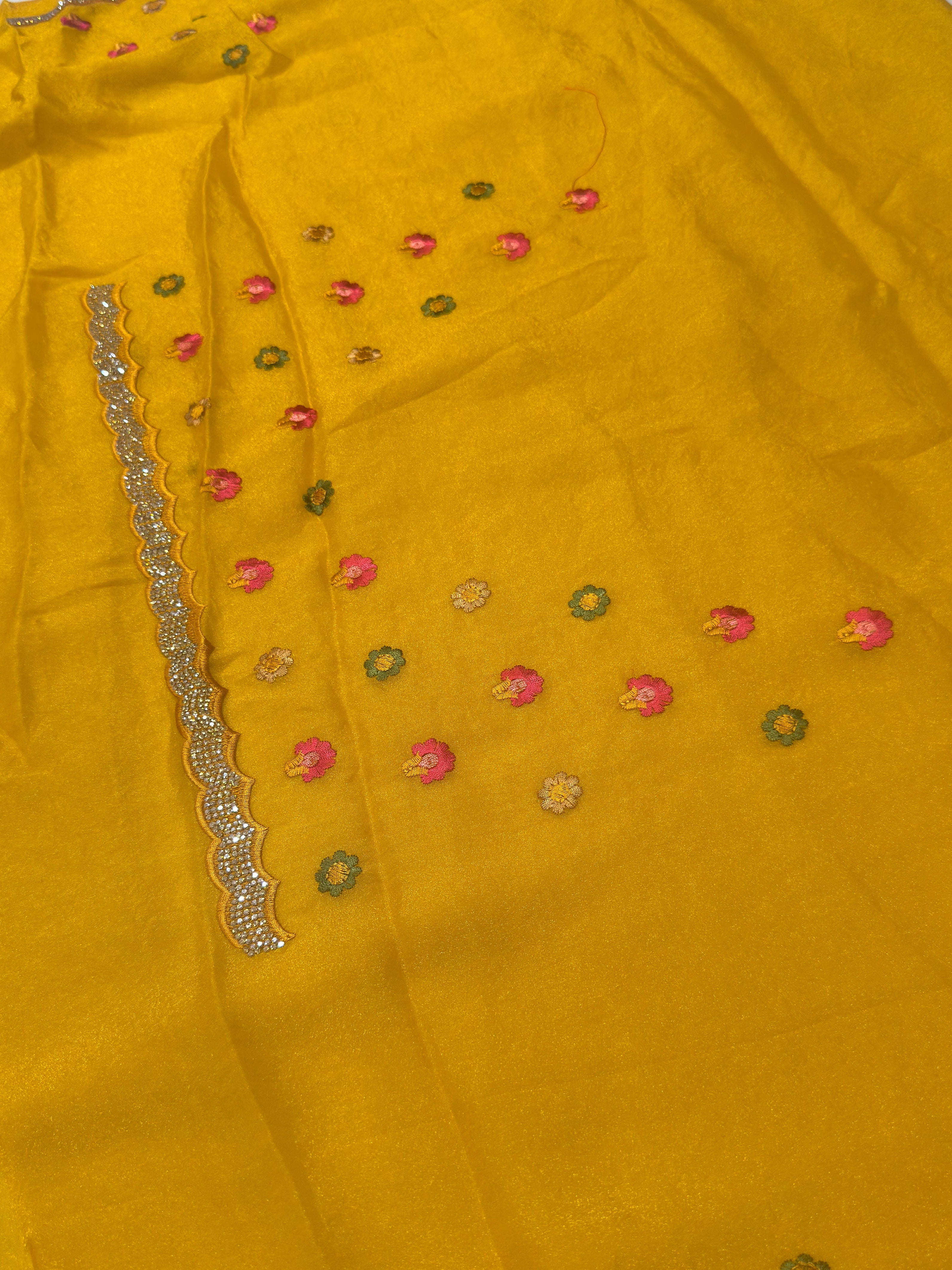 Yellow fabric with floral embroidery and a decorative border.