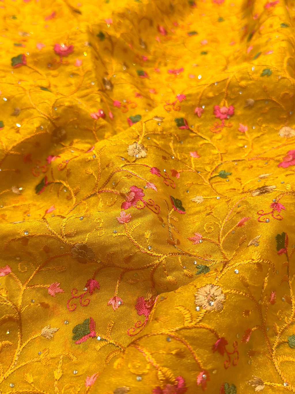 Close-up of yellow fabric with floral embroidery and sequins