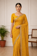 Woman wearing a yellow saree with a gold border indoors.