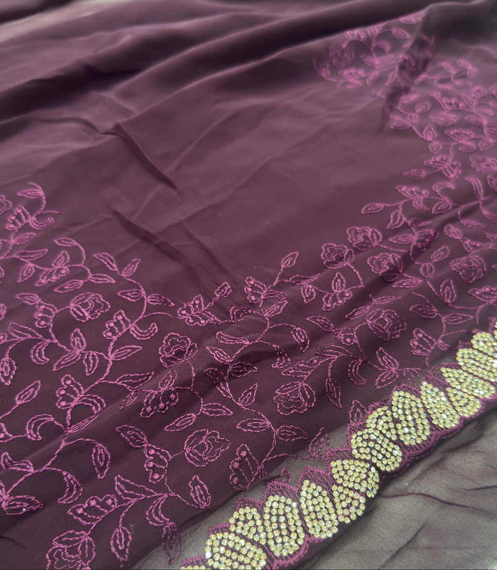 Purple fabric with pink floral patterns and green beadwork on a dark background