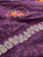 Close-up of a purple fabric with floral patterns and bead embellishments