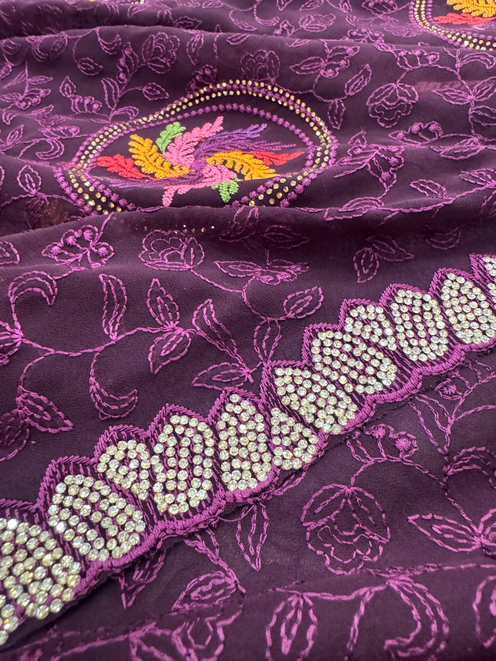 Close-up of a purple fabric with floral patterns and bead embellishments