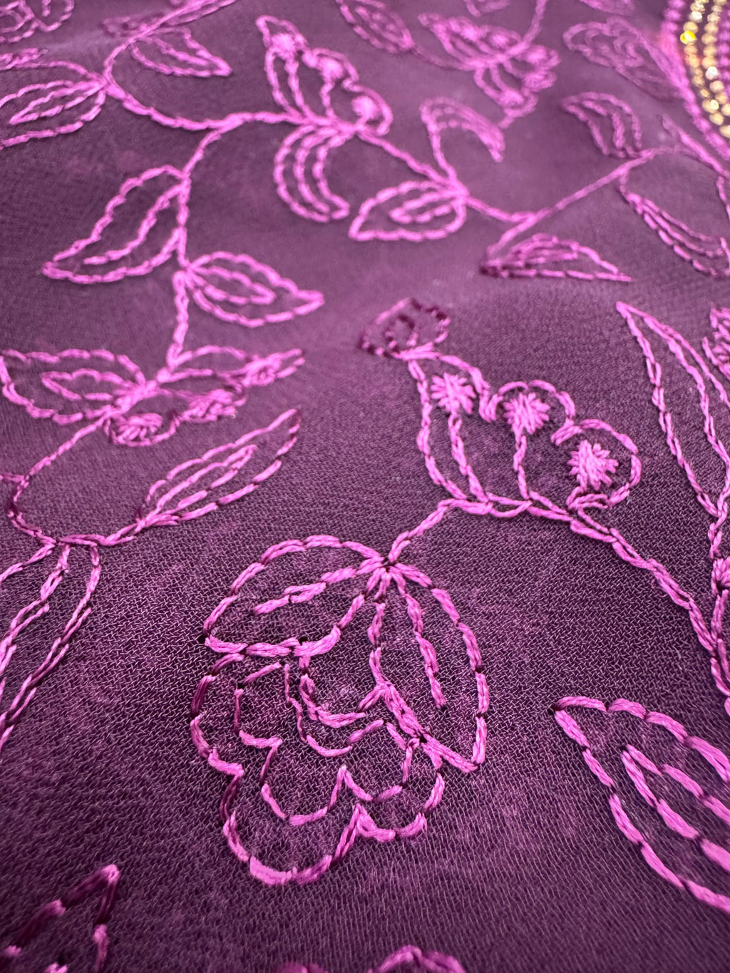 Close-up of purple fabric with pink floral embroidery