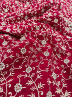 Red fabric with intricate white floral embroidery