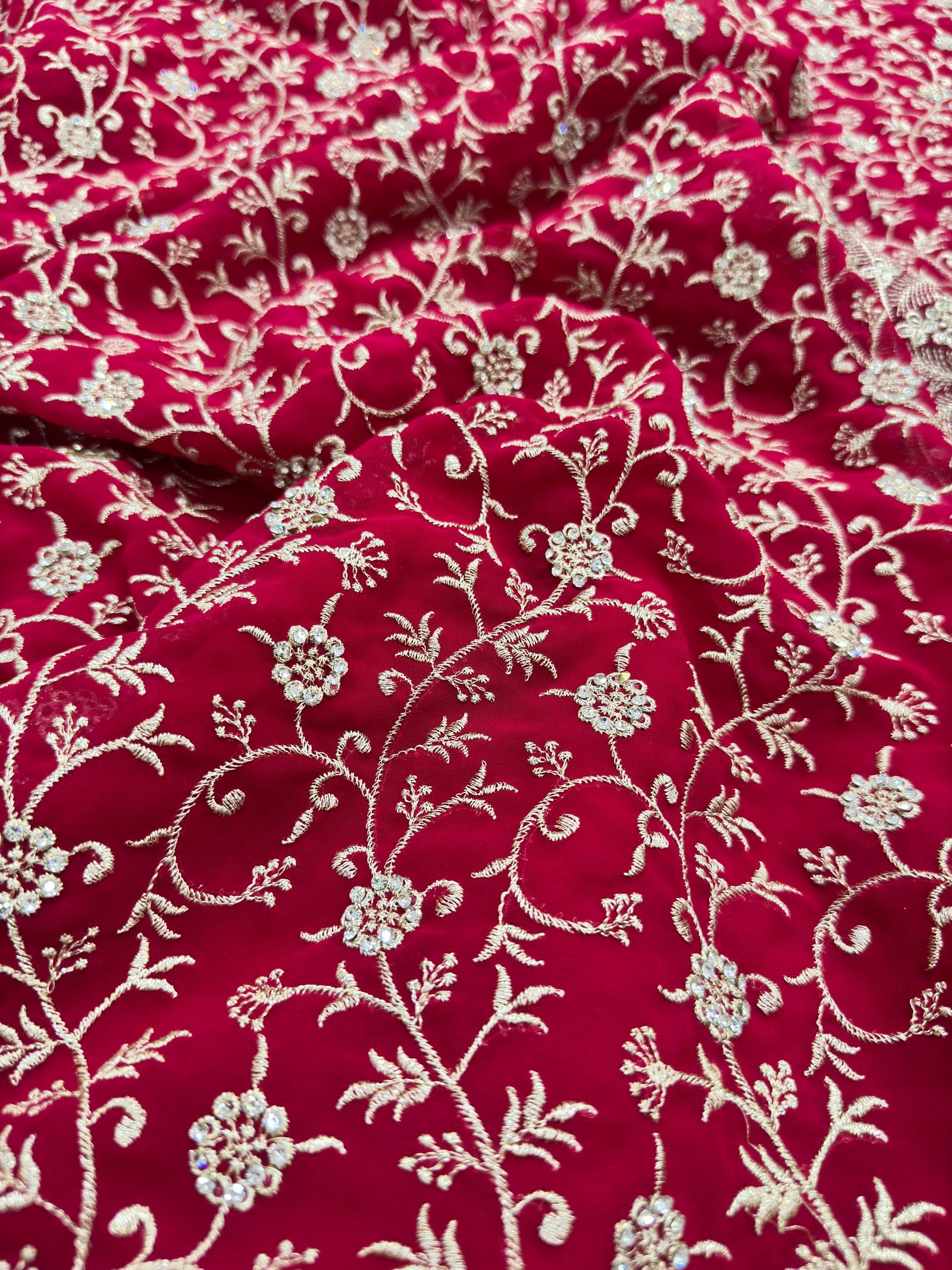 Red fabric with intricate white floral embroidery