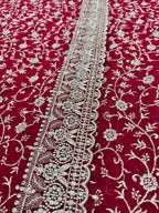 Red fabric with intricate white floral patterns and a border