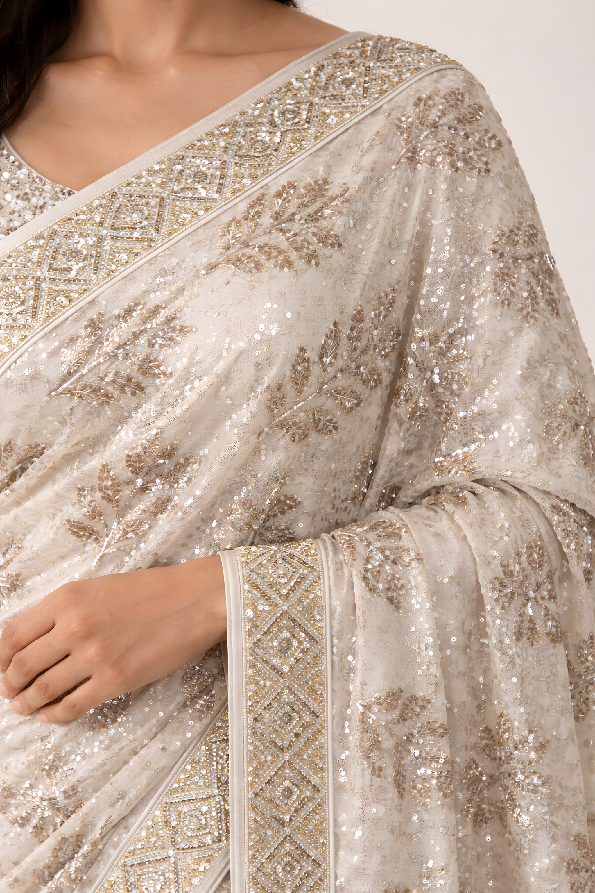 Close-up of a silver saree with intricate patterns on a white background