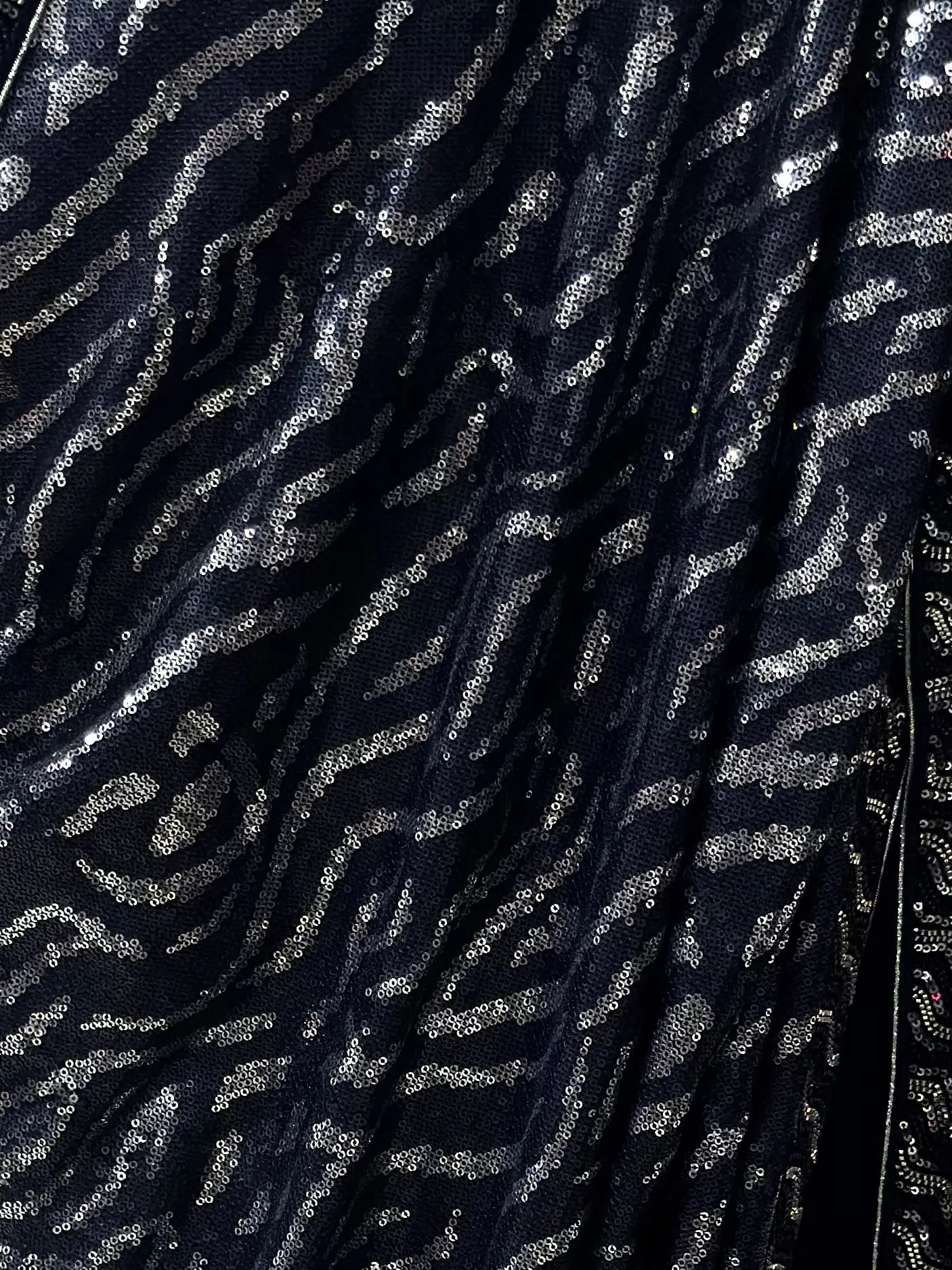 Close-up of a dark fabric with silver sequin pattern