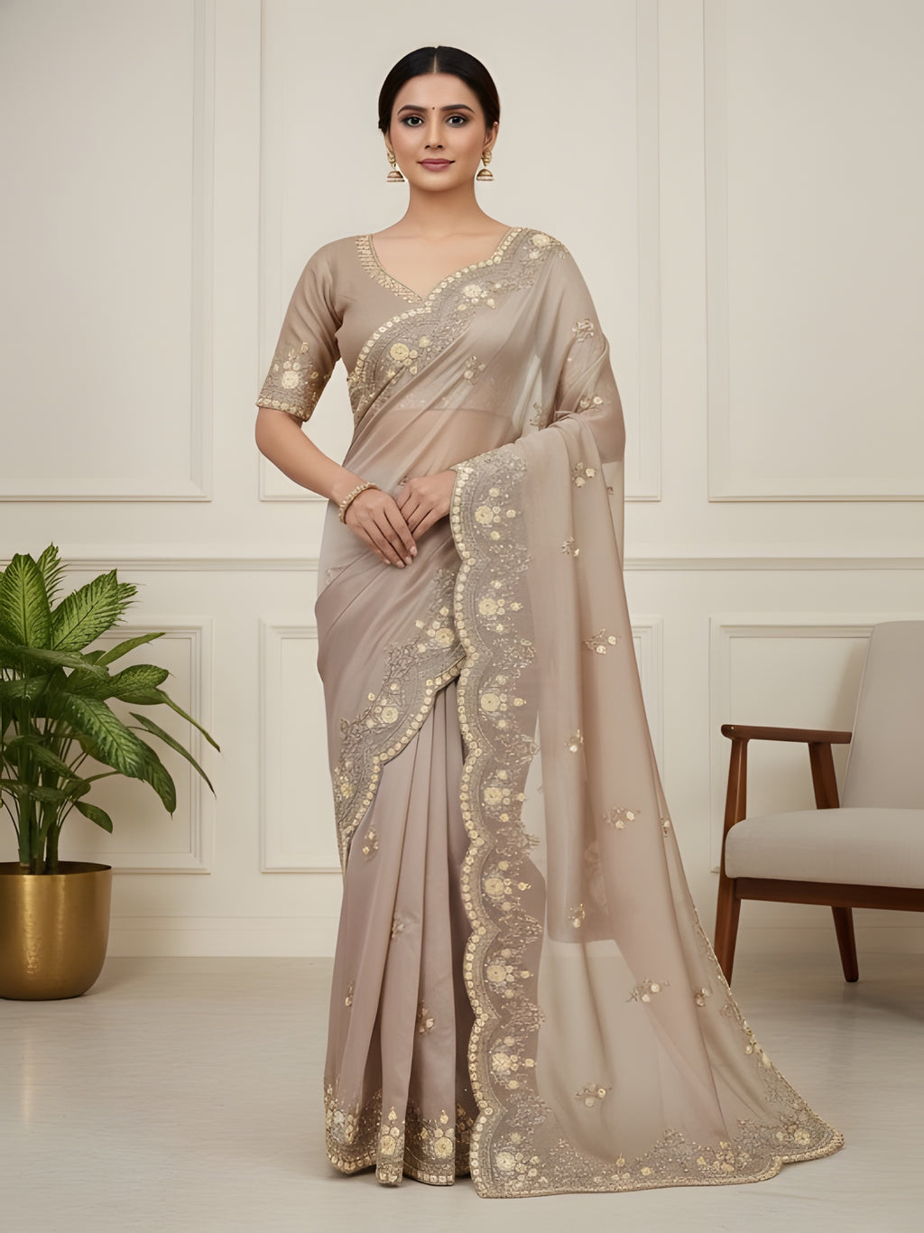 Woman wearing a beige saree with gold embroidery in a minimalistic room.