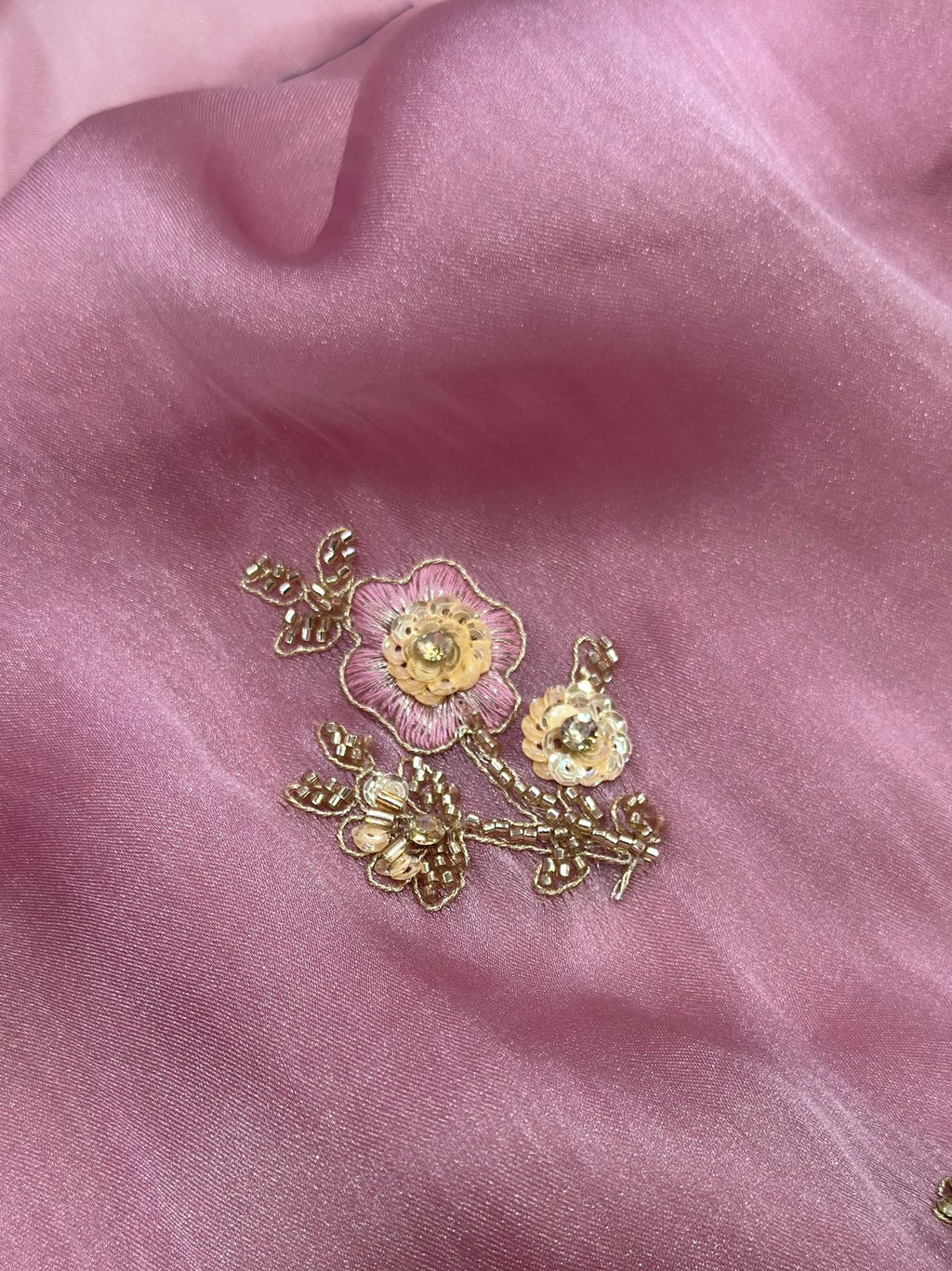 Gold floral brooch on pink fabric