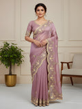 Woman wearing a mauve saree with gold embroidery in a room setting.