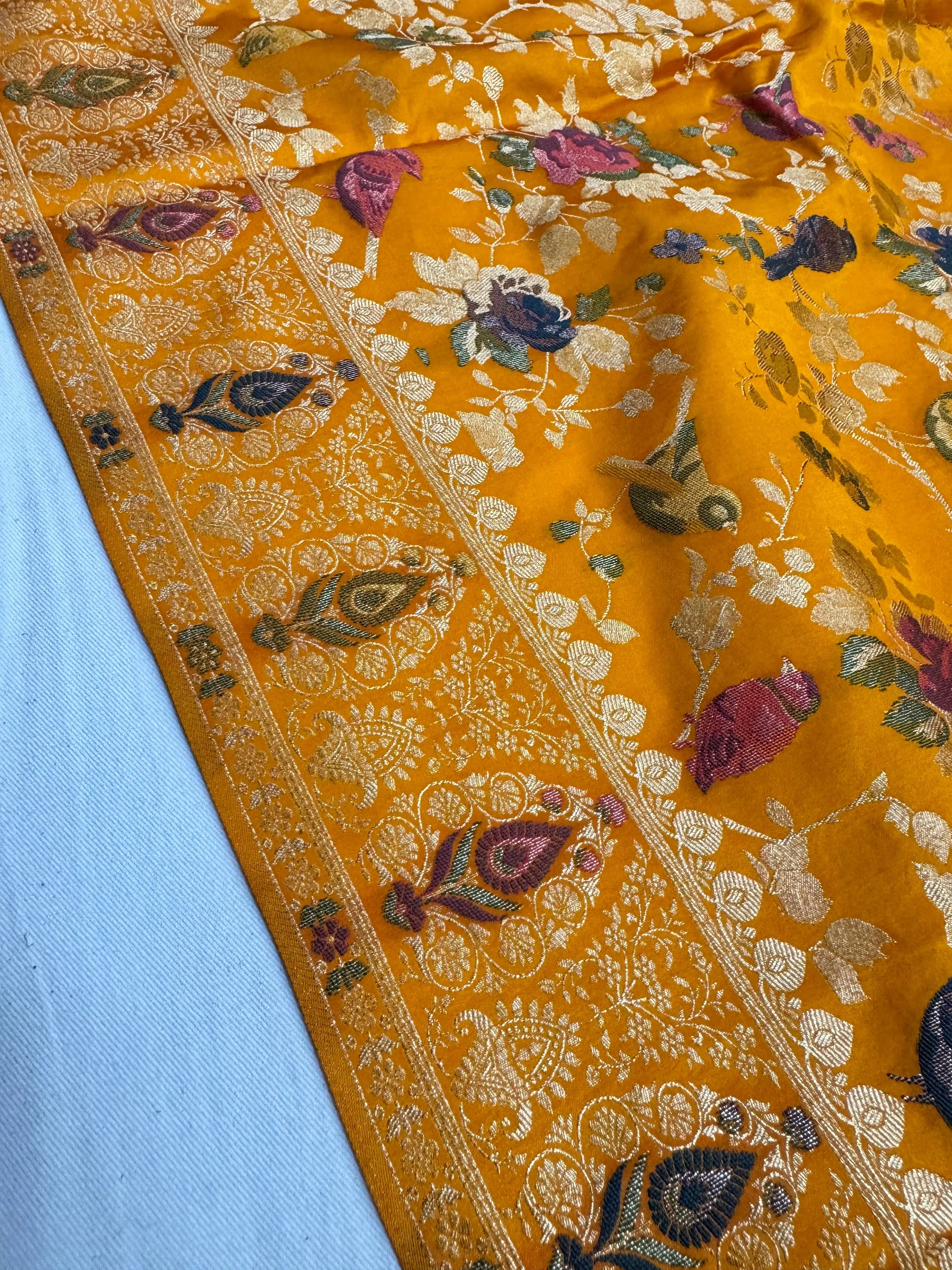Close-up of a yellow fabric with intricate floral patterns on a blue background