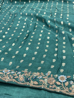 Teal fabric with white floral patterns and intricate gold embroidery.