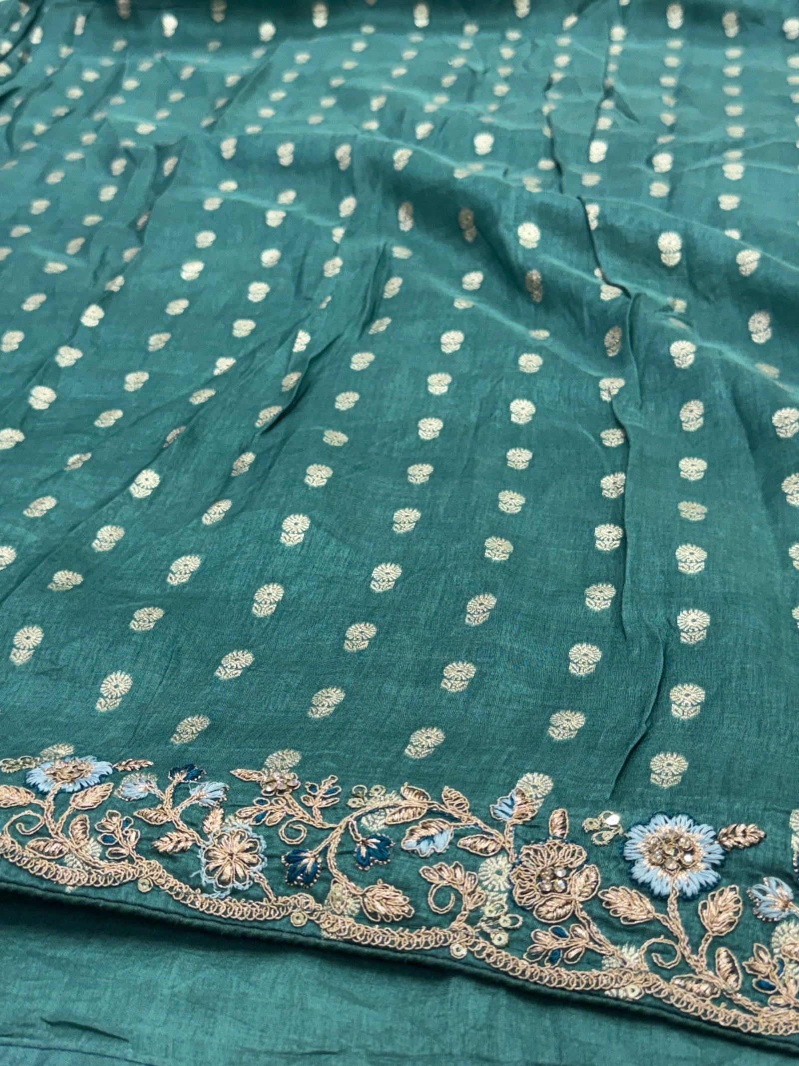 Teal fabric with white floral patterns and intricate gold embroidery.