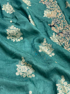 Teal fabric with intricate white floral embroidery