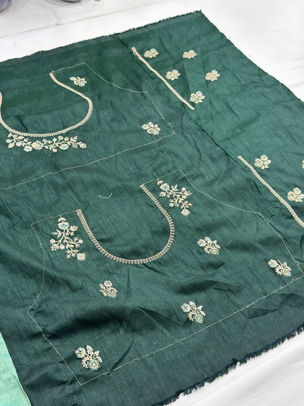 Green fabric with white embroidery on a white background