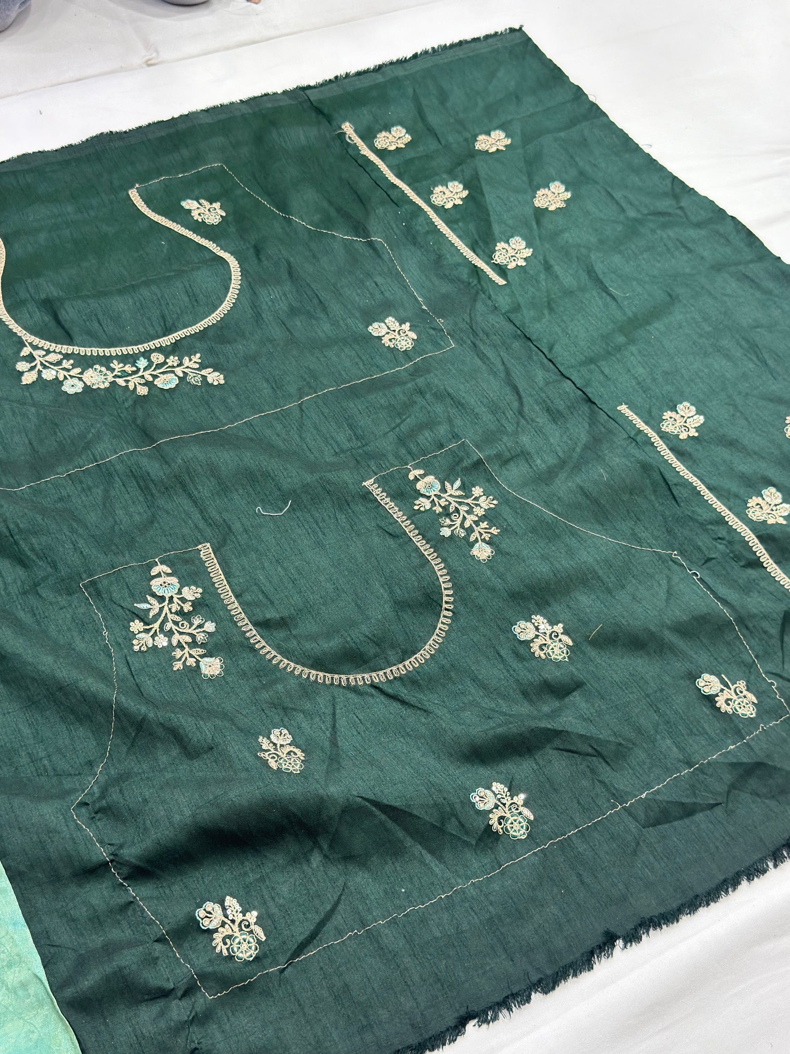 Green fabric with white embroidery on a white background