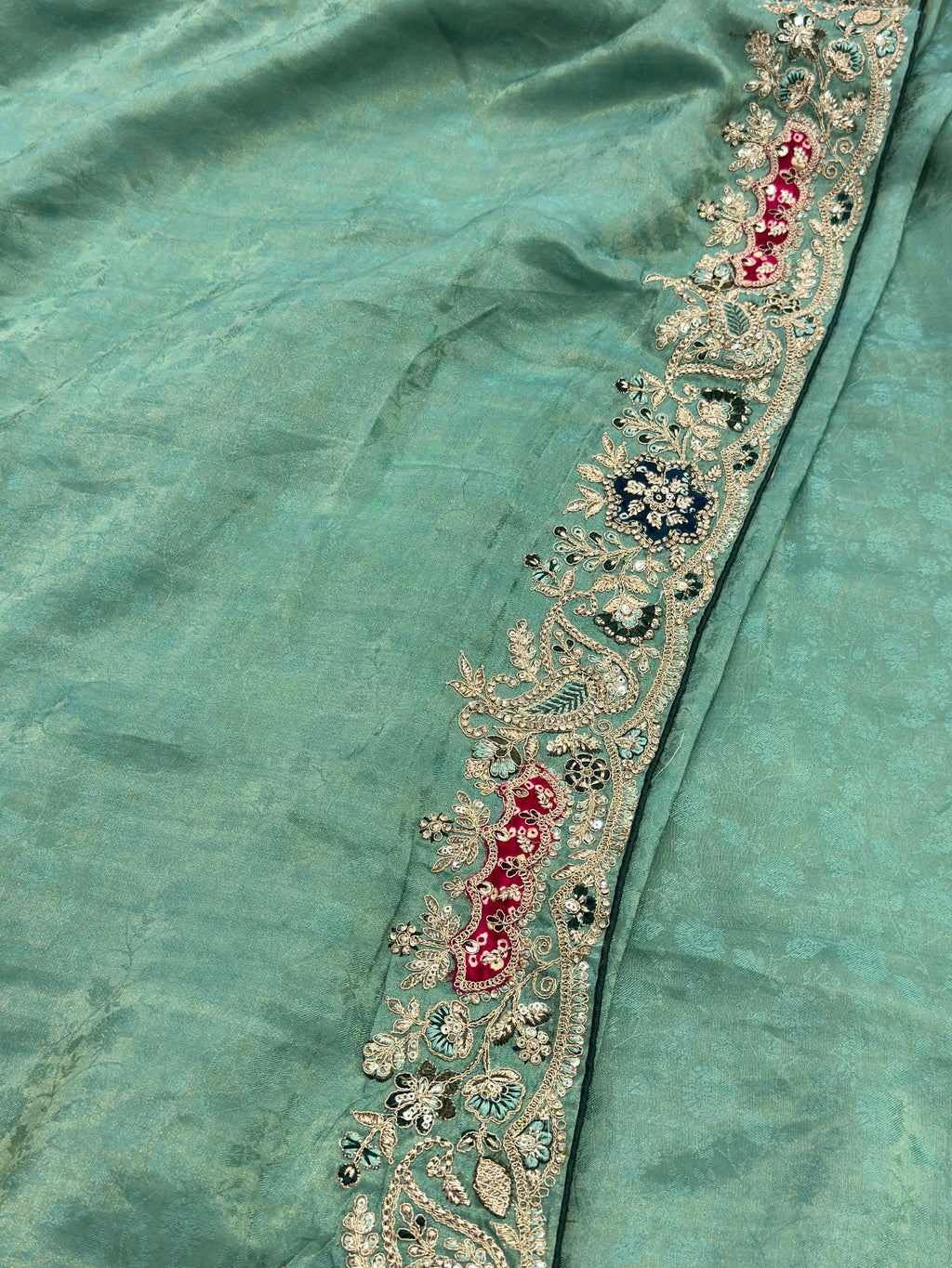 Teal fabric with intricate gold and red embroidery