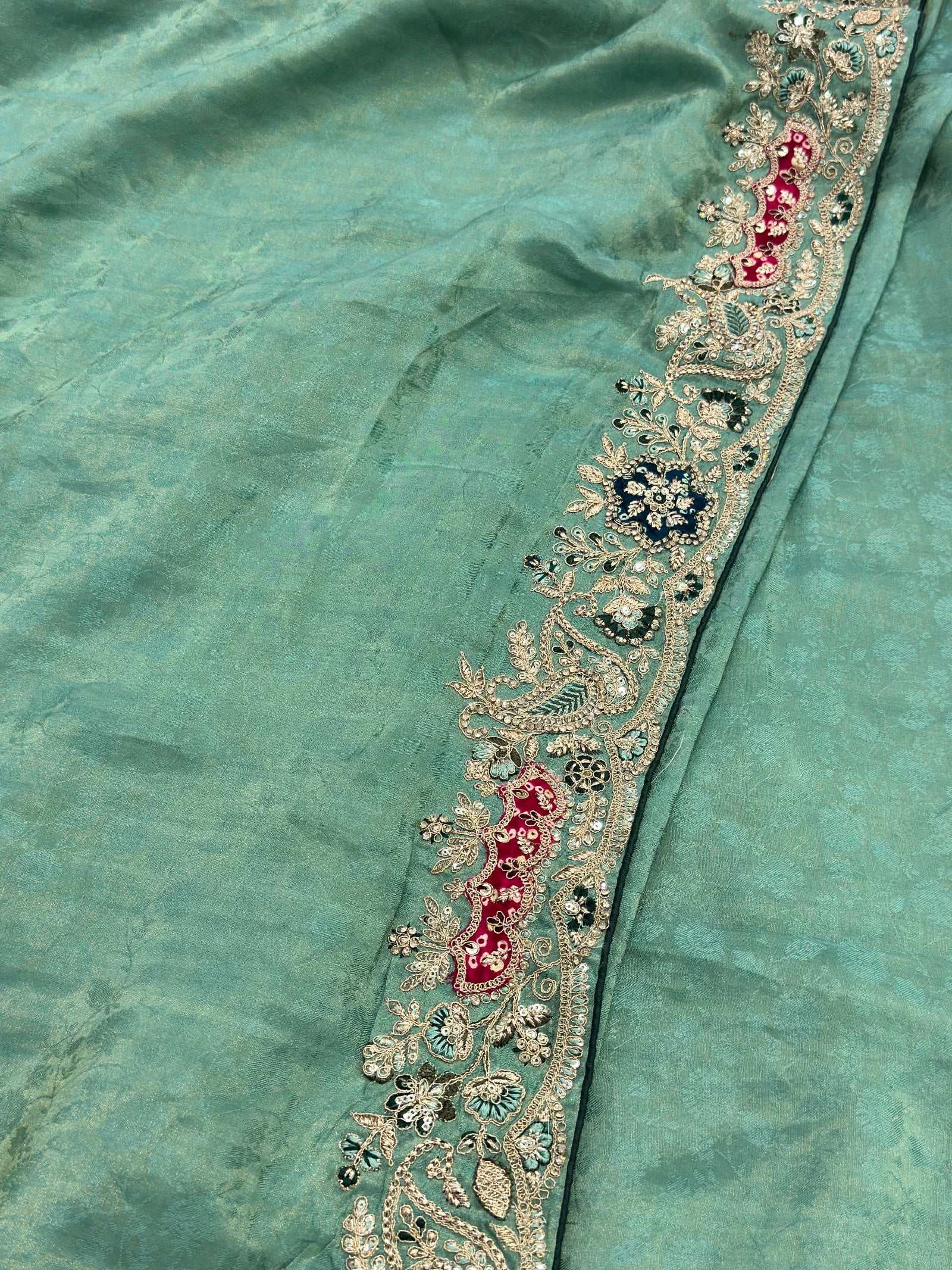 Teal fabric with intricate gold and red embroidery