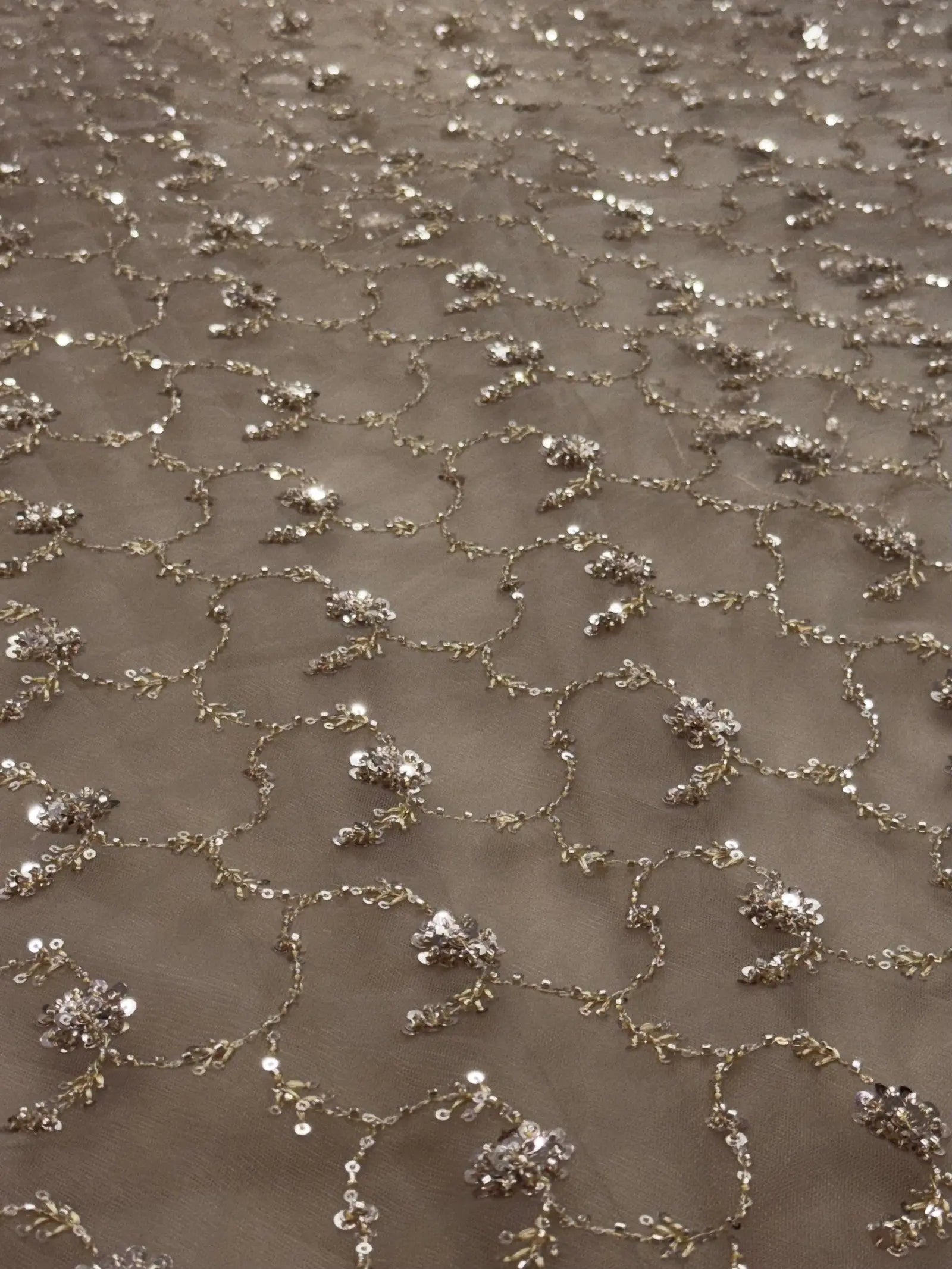 Close-up of a textured fabric with small embellishments on a beige background