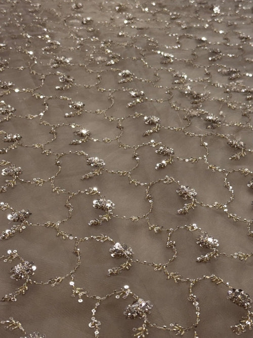 Close-up of a textured fabric with small embellishments on a beige background