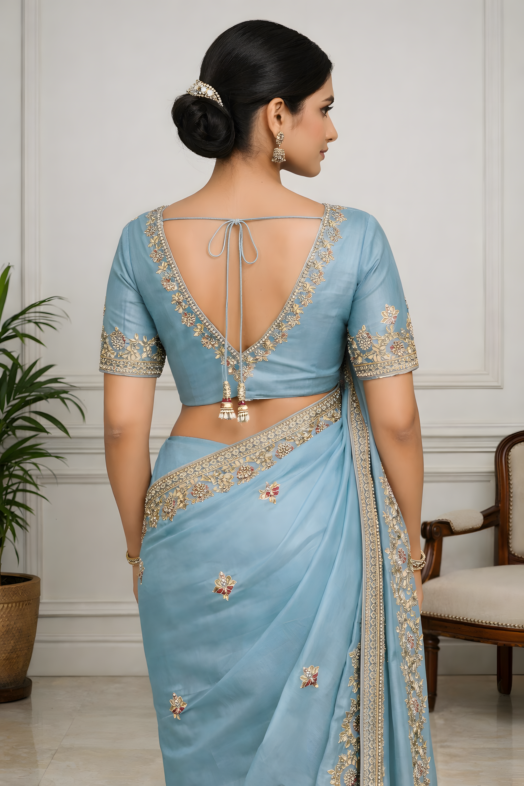 Woman wearing a light blue saree with intricate designs in an indoor setting.