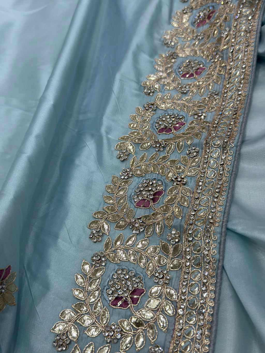 Decorative fabric border with gold embroidery on a light blue background
