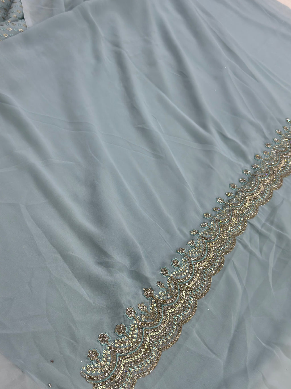 Light blue fabric with gold embroidery along the edge