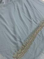 Light blue fabric with gold embroidery along the edge