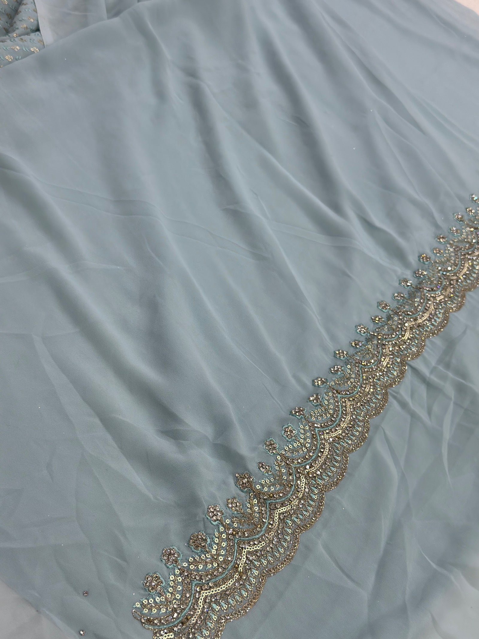 Light blue fabric with gold embroidery along the edge