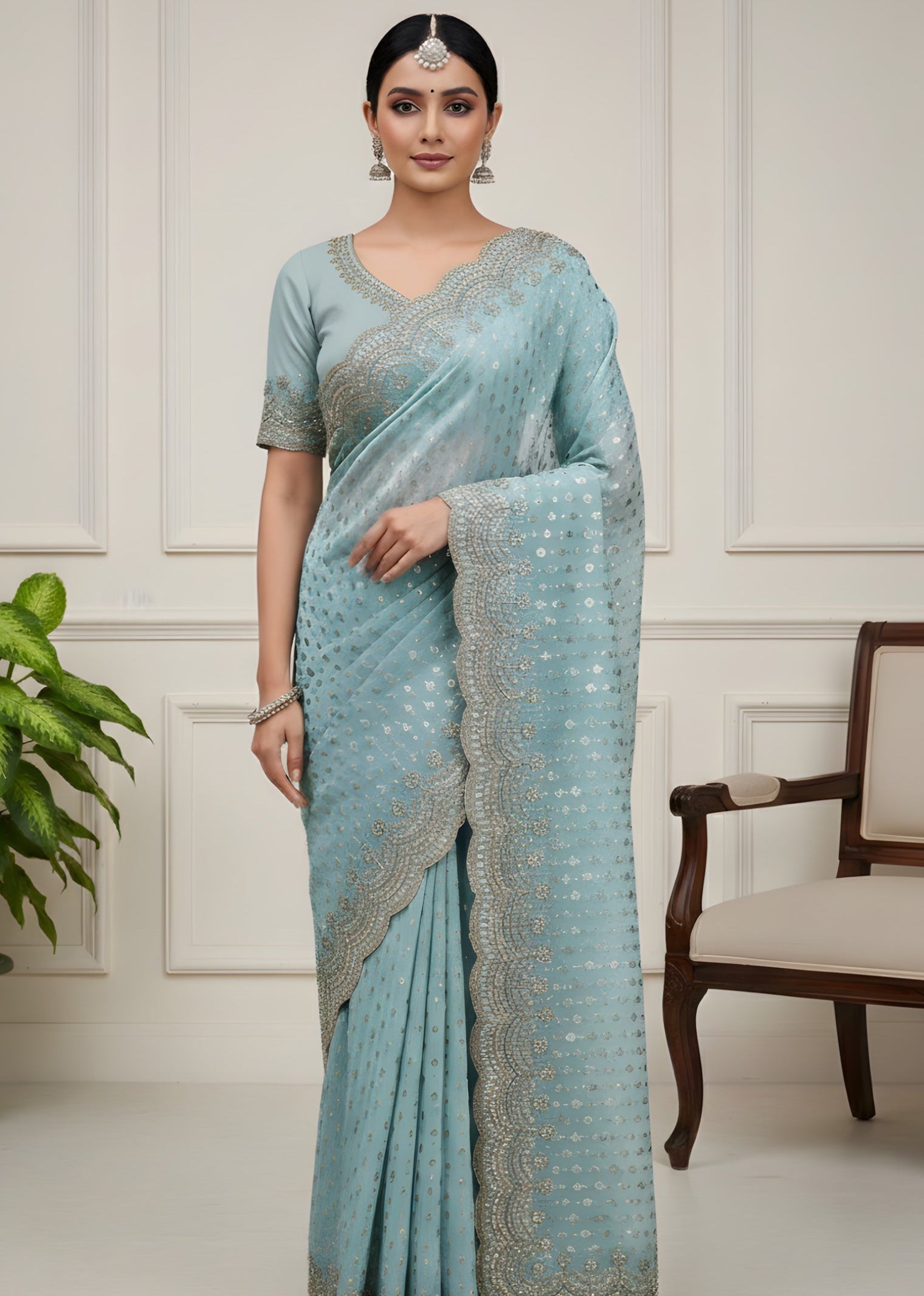 Woman wearing a light blue saree with silver patterns in a minimalistic setting.