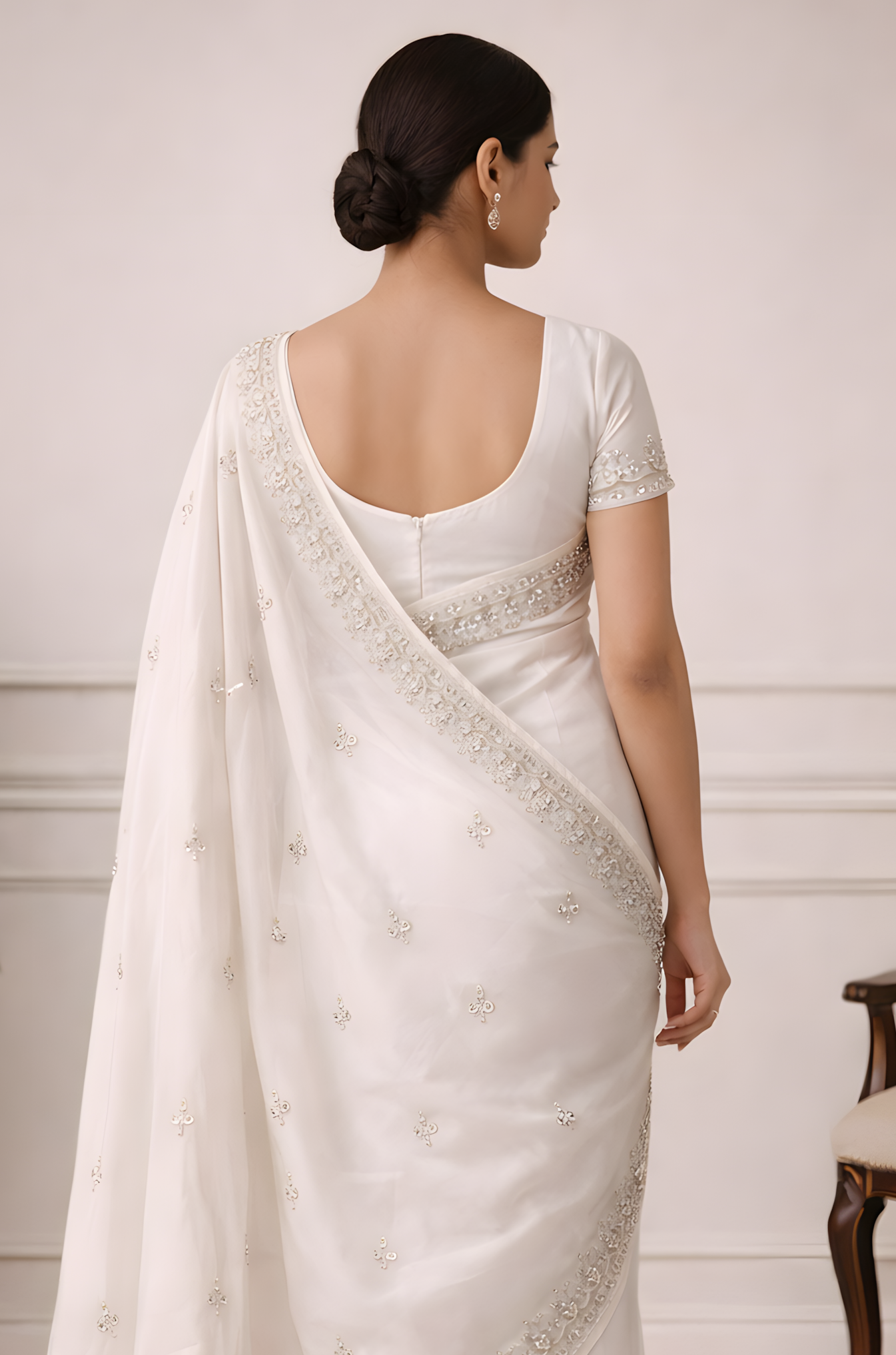 Woman wearing a white saree with a plain background