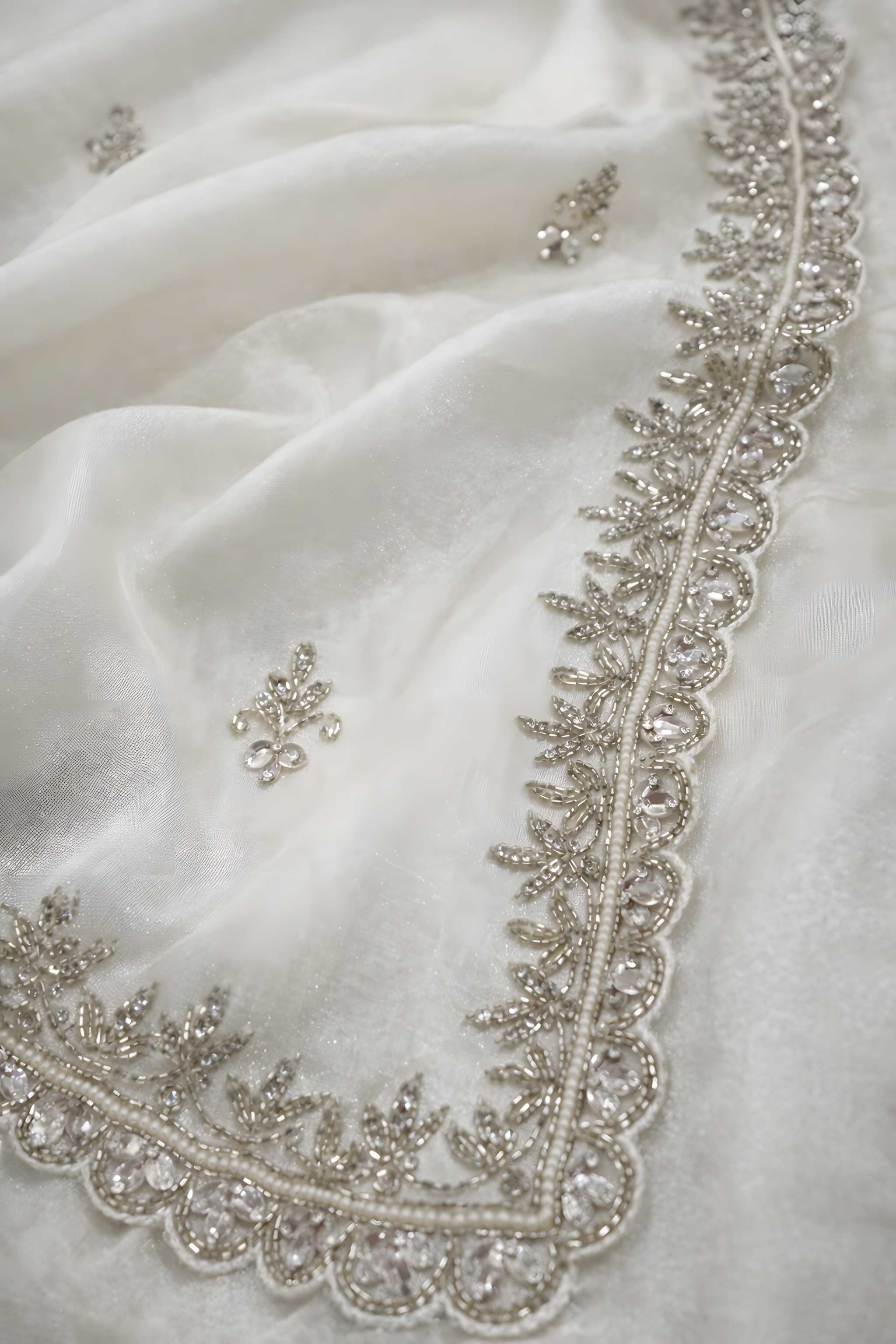 Close-up of a white fabric with intricate silver embroidery