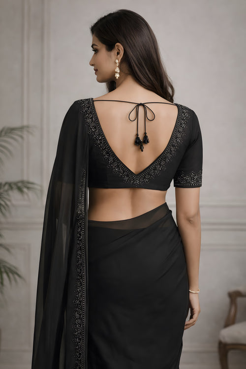 Woman wearing a black saree with intricate detailing in a neutral setting