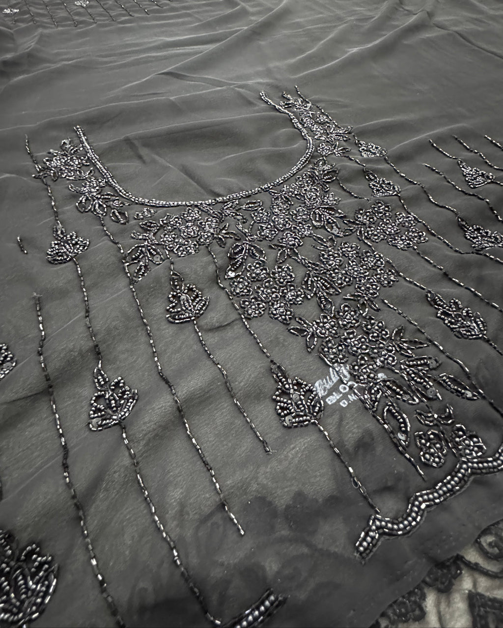 Close-up of a black embroidered garment with intricate patterns.